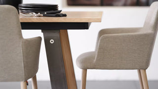 Détail de chaises à accoudoirs Mobitec Rob gris clair à une table en bois au piètement noir