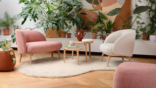 Lifestyle image of a pink Mobitec Thalia sofa and ecru armchair among plants