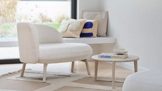 Lifestyle image of an ecru Mobitec Thalia loveseat with cushions and coffee table in a bright living room