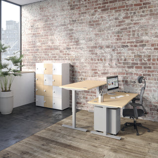 Sfeerbeeld van een Buronomic Locker Eko kast in wit en beuk naast een zit-sta bureau voor bakstenen muur