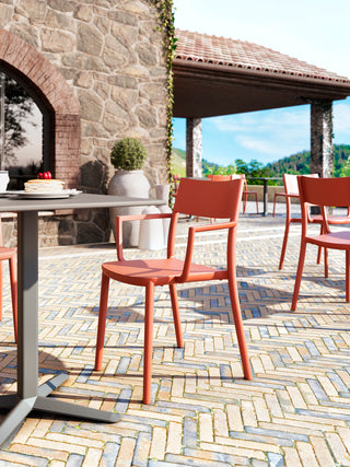 Lifestyle image of orange Gaber To-Me chairs on a terrace by a stone building
