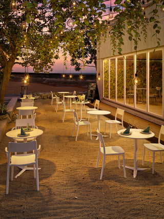 Sfeerbeeld van witte Gaber To-Me stoelen rond bistrotafels op een terras bij avond