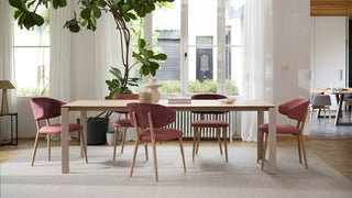Lifestyle image of pink Mobitec Toro chairs at a long wooden table in a bright room